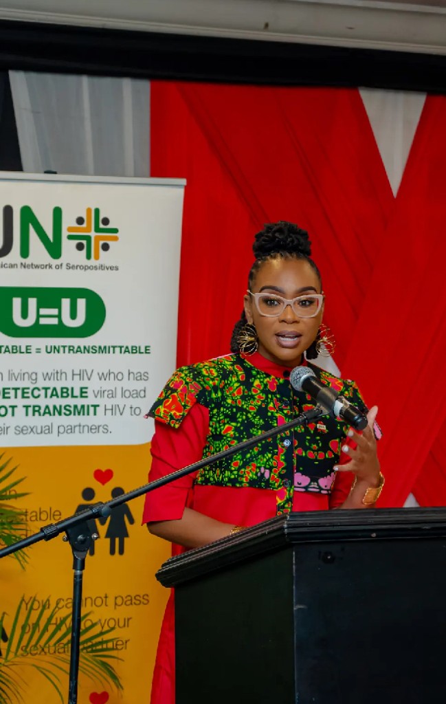 Krystal speaking at a podium with UN and public health messaging in the backdrop.